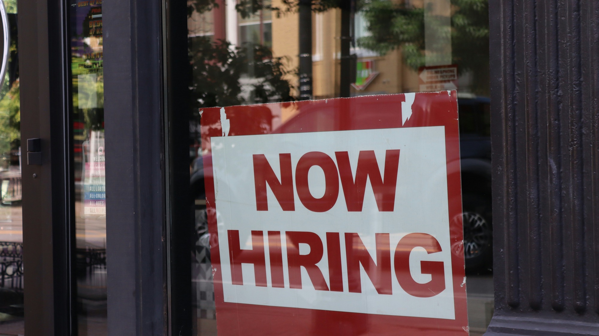 Now hiring sign in a storefront window